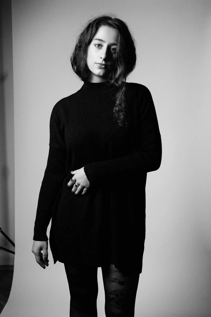 Woman with a short bob in a black sweater in a knee-length monochrome portrait