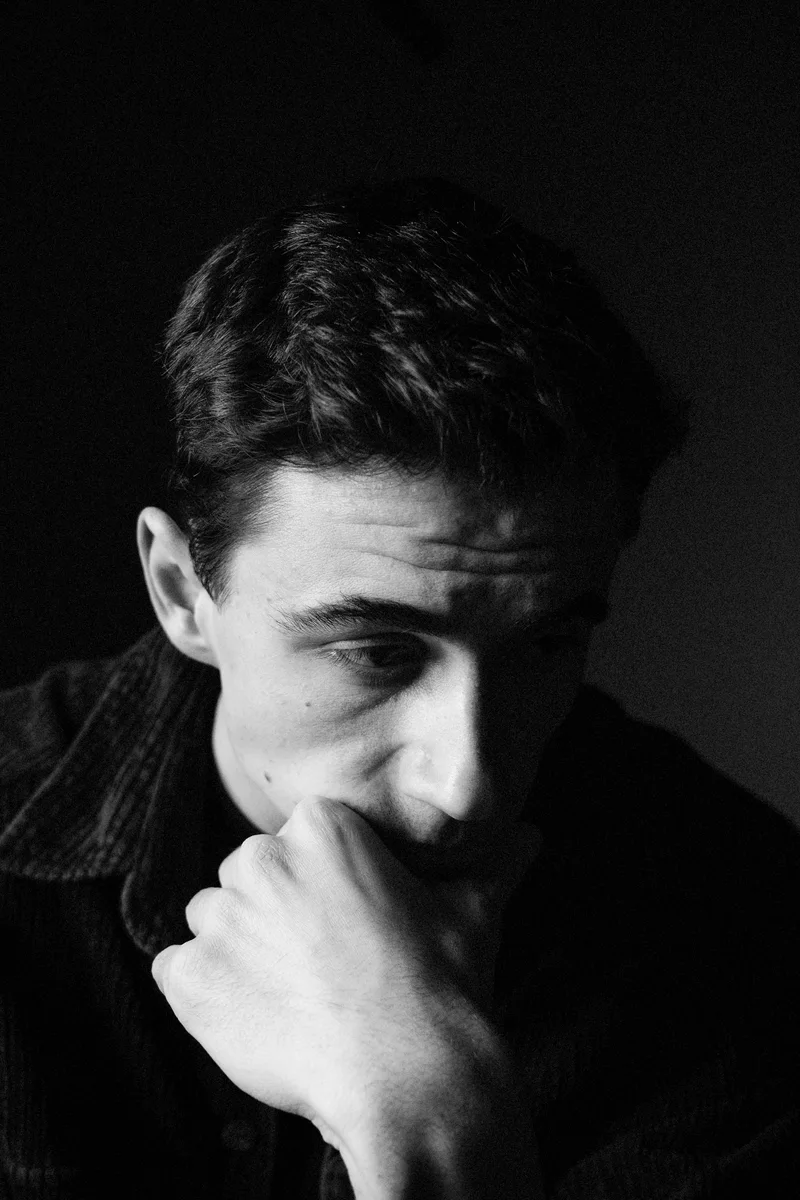 Pensive man with his fist to his mouth in darkness
