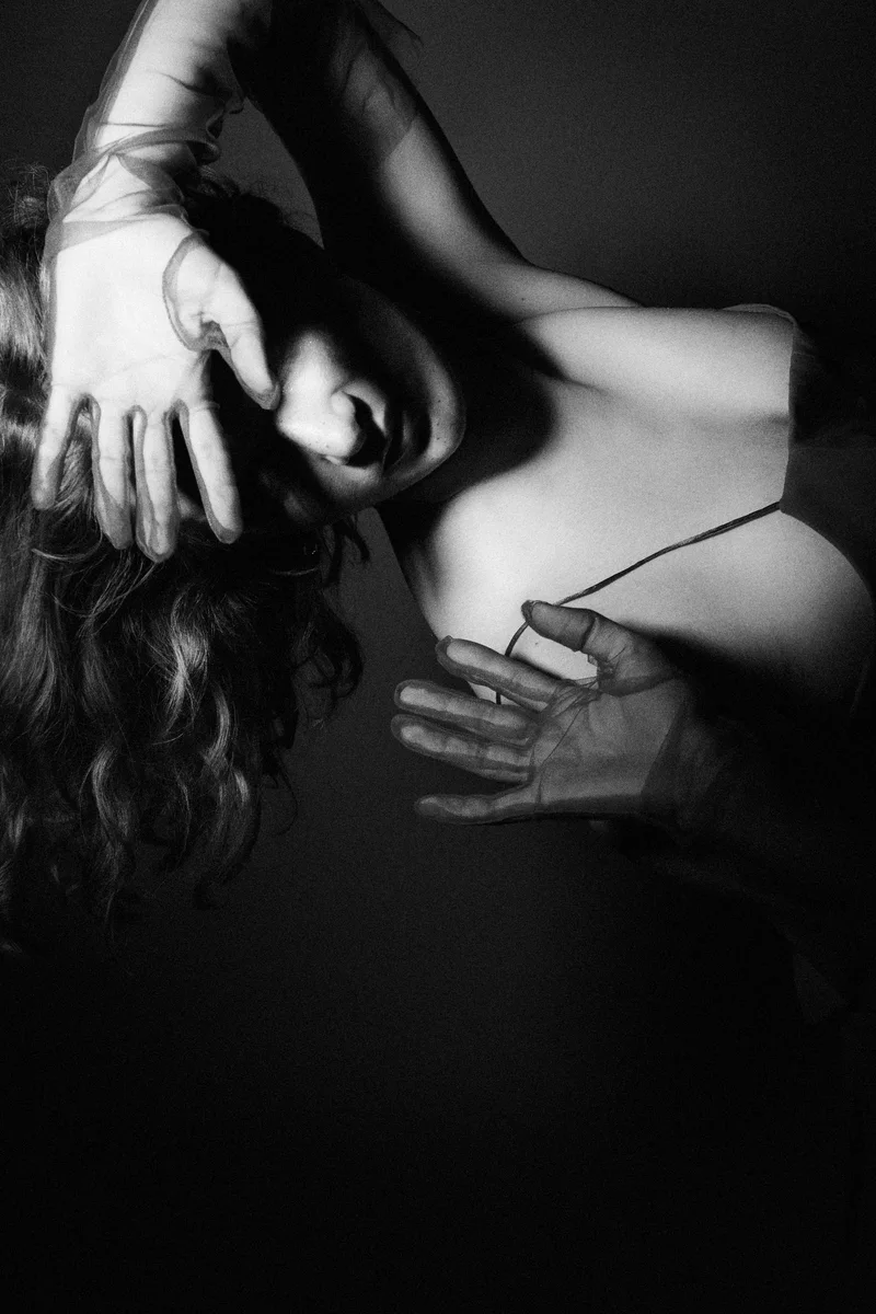 Woman reclining with her arm over her face and a sheer sleeve