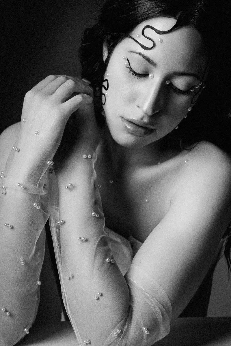 Woman with closed eyes, sheer sleeves and a painted curl on her forehead