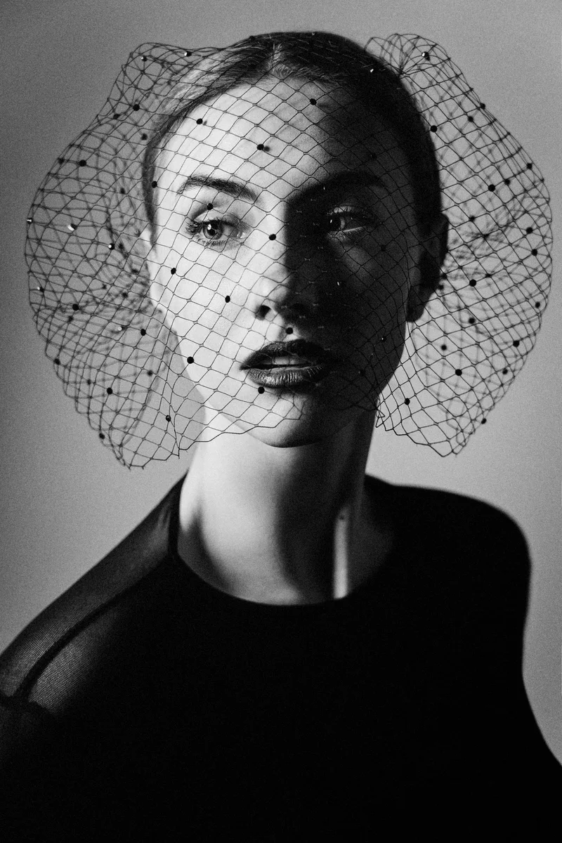 Woman with a round net veil and dark drapery in side light