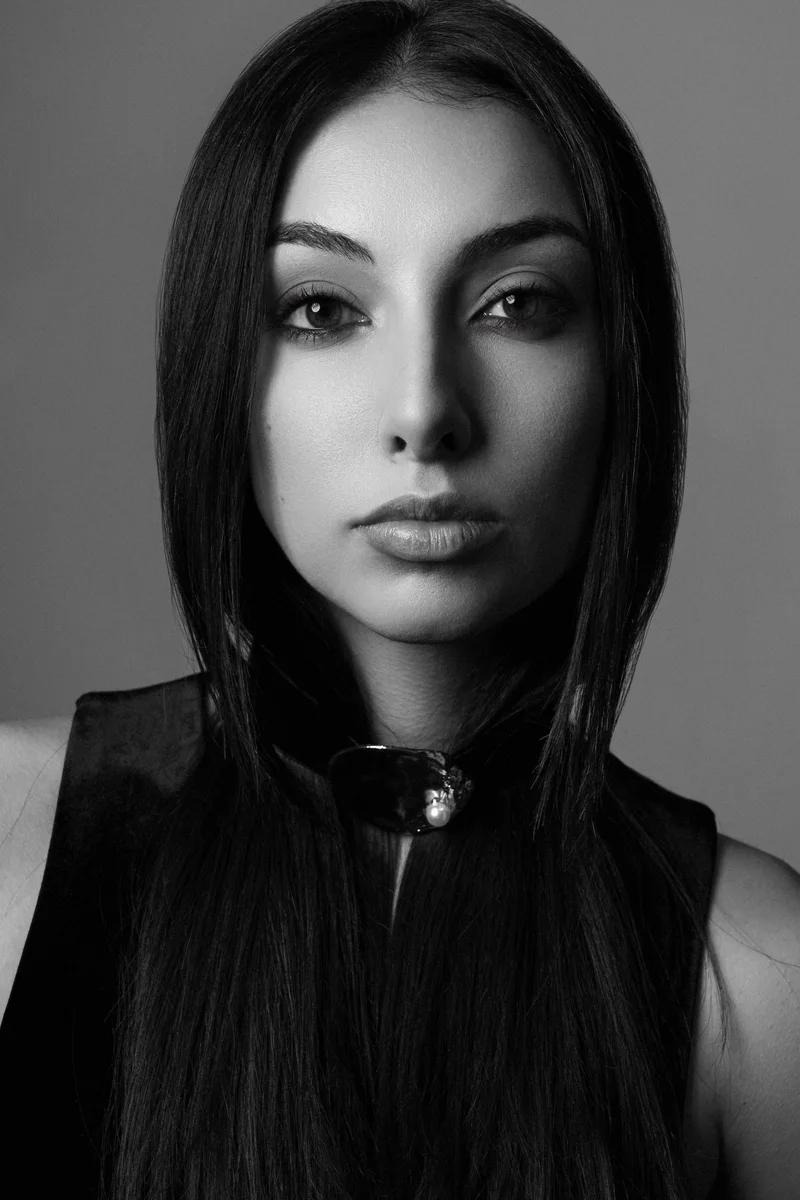 Woman with long straight hair and a black zipped top in a monochrome portrait