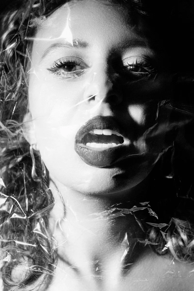 Woman's face with dark lips behind a transparent crumpled texture