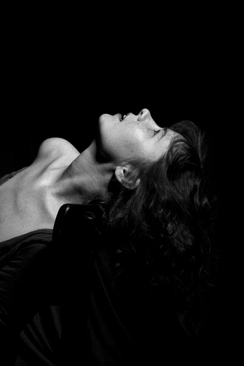 Woman with her head thrown back and her eyes closed in darkness