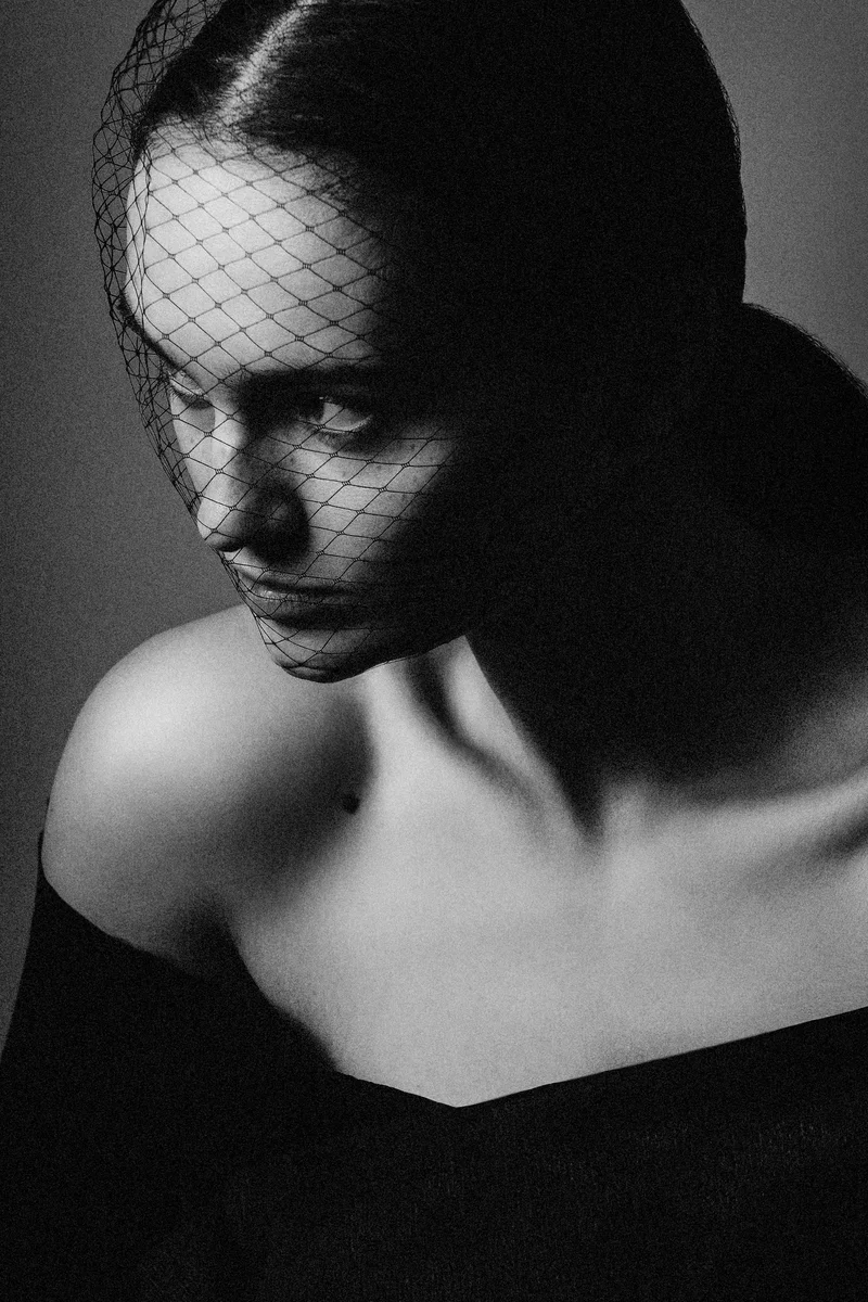 Woman with a net veil and bare shoulders, looking down
