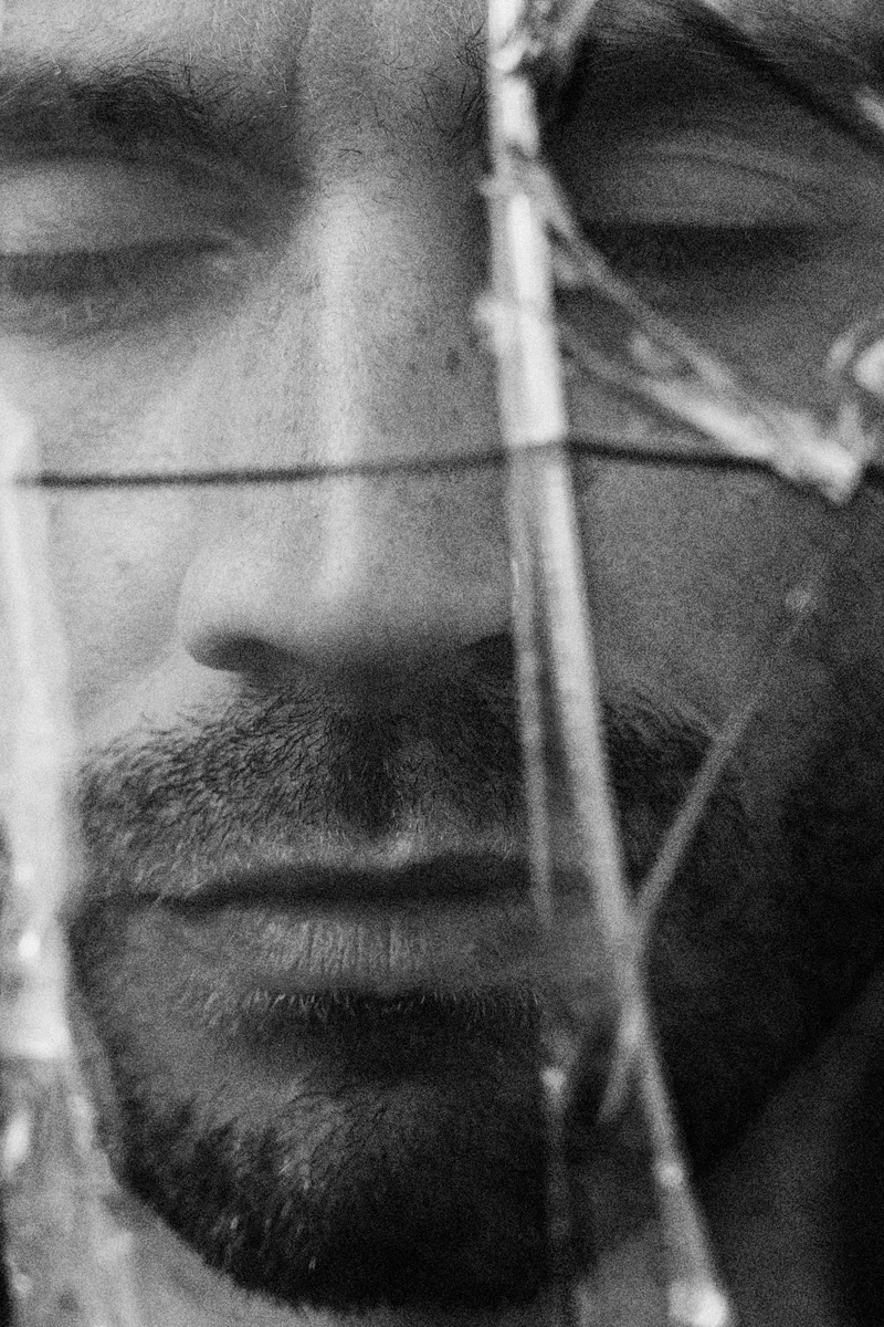 Man's face with closed eyes behind dry twigs