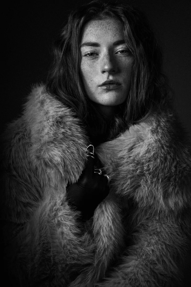 Freckled woman with long hair wrapped in a fur coat