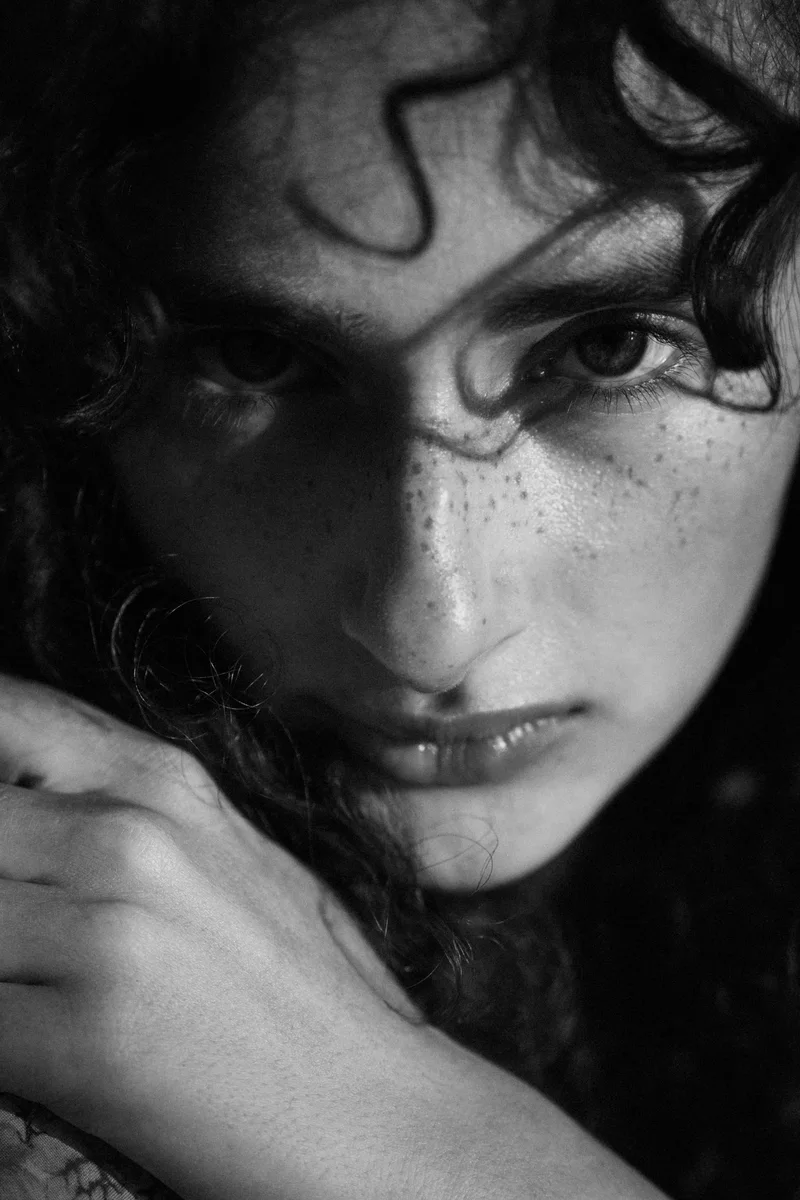 Close portrait of a freckled woman with curls falling over her eye