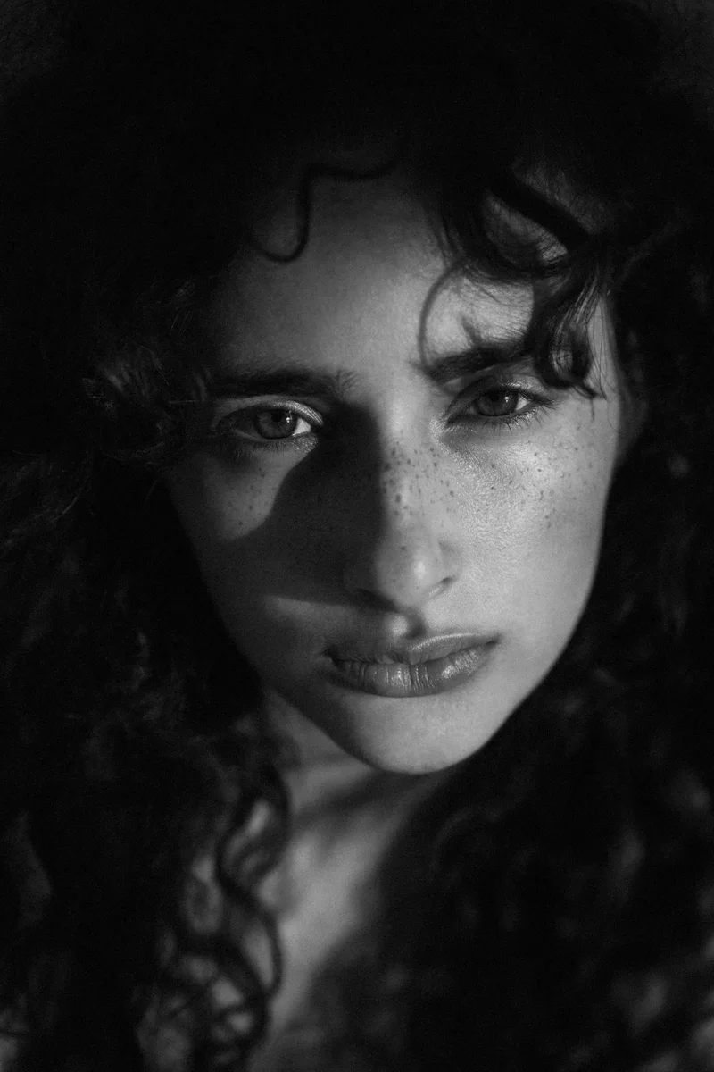 Freckled woman with curly hair looking straight into the camera