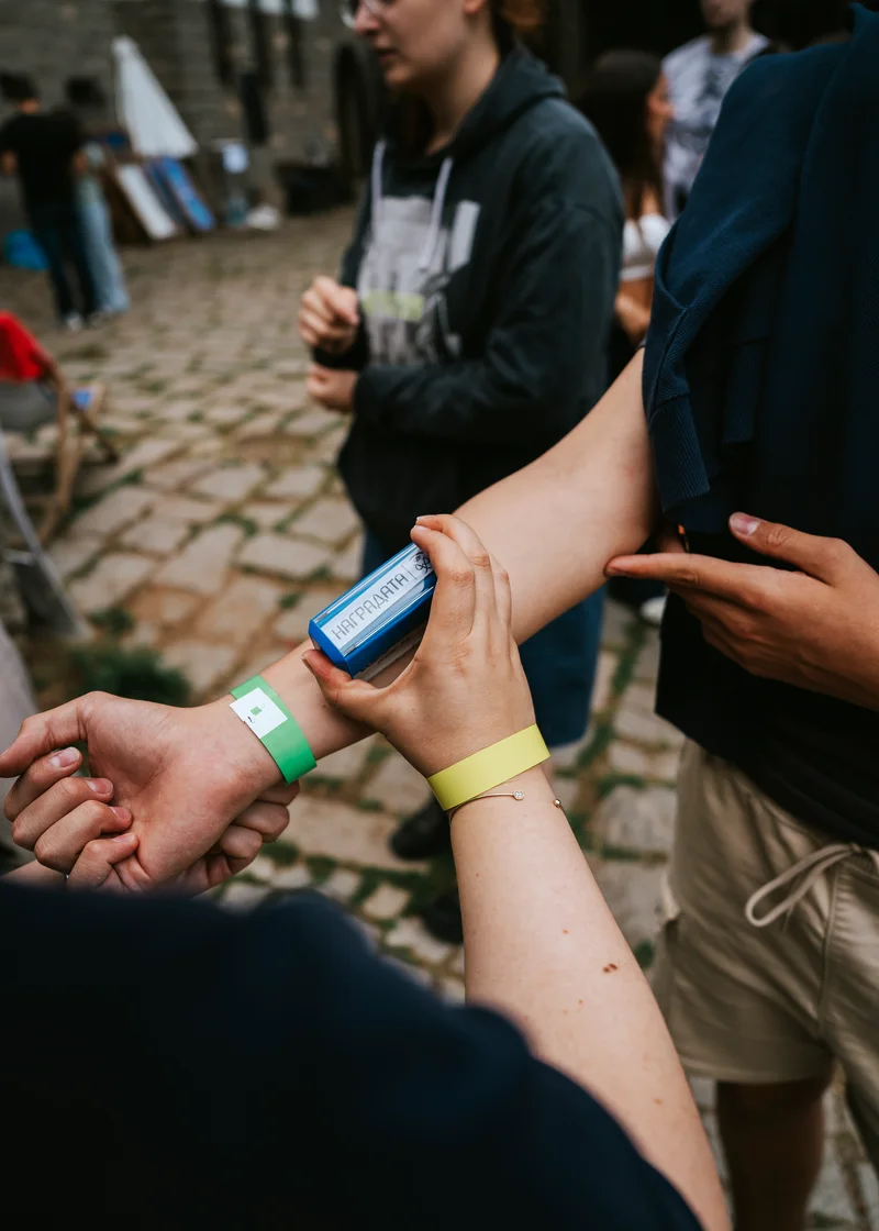 A participant's arm being stamped, coloured wristbands on their wrists