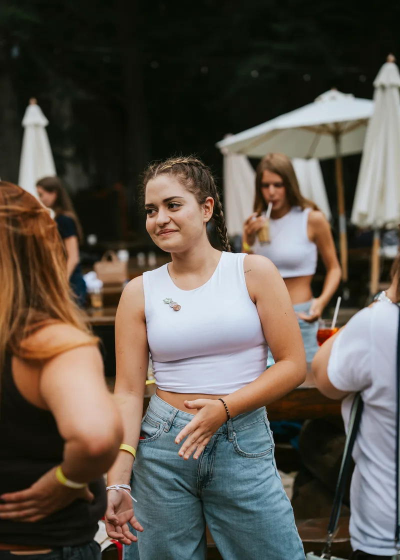 Smiling woman with braids in a white top among guests under parasols