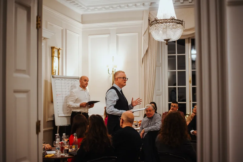 Two hosts beside a flip chart addressing the guests at their tables