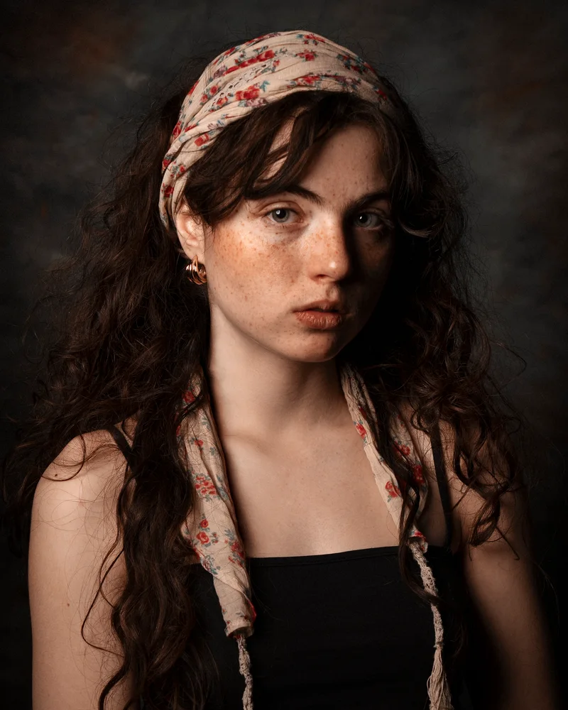 Freckled woman with long curly hair and a floral headscarf