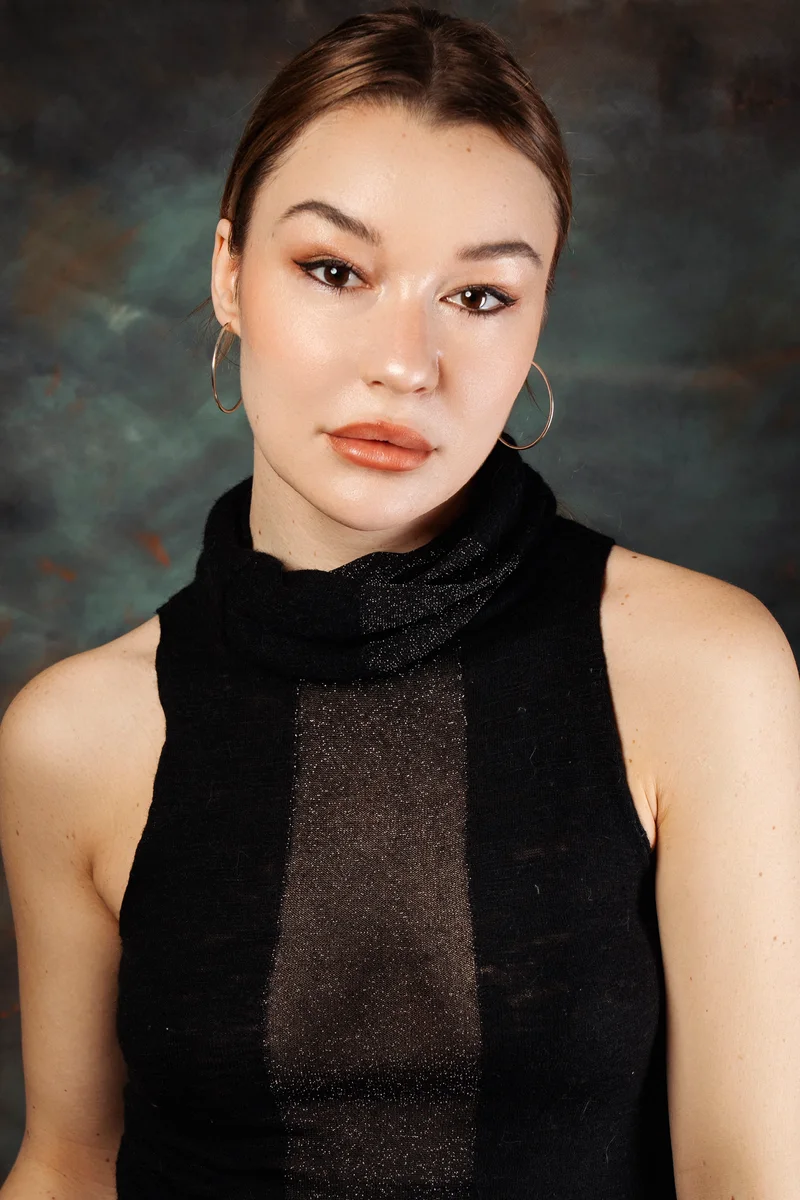 Woman with tied-back hair, hoop earrings and a black knit top