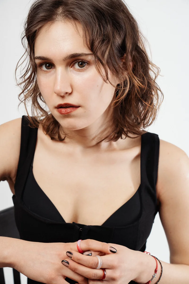 Woman with short wavy hair in a black top holding her hands together