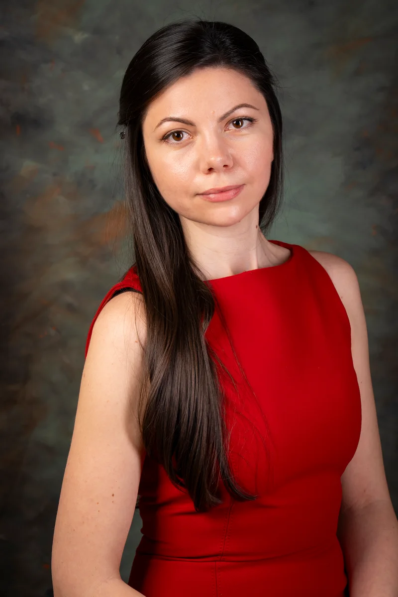 Woman in a red dress with long dark hair, turned towards the camera