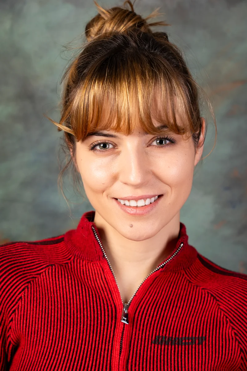 Smiling woman with a bun and fringe in a red zipped top