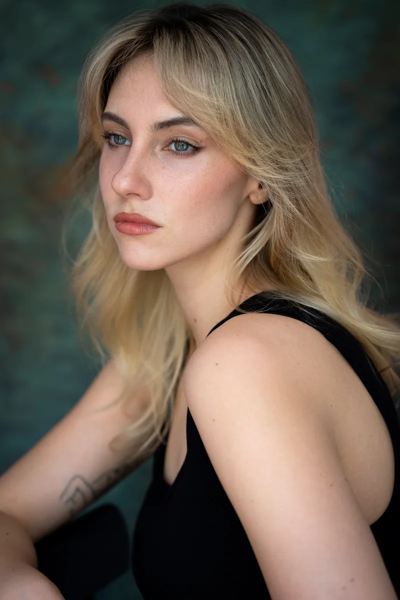 Blonde woman with loose hair in a black top looking to the side