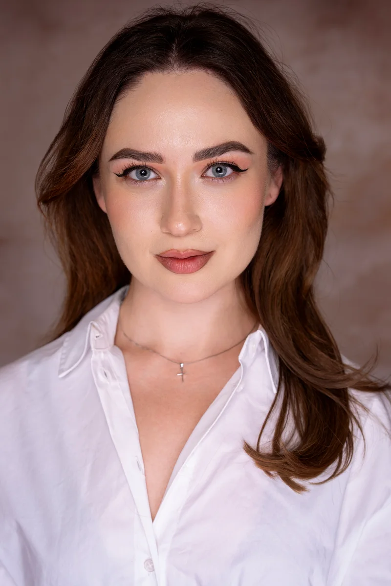 Woman with brown hair in a white shirt looking straight into the camera