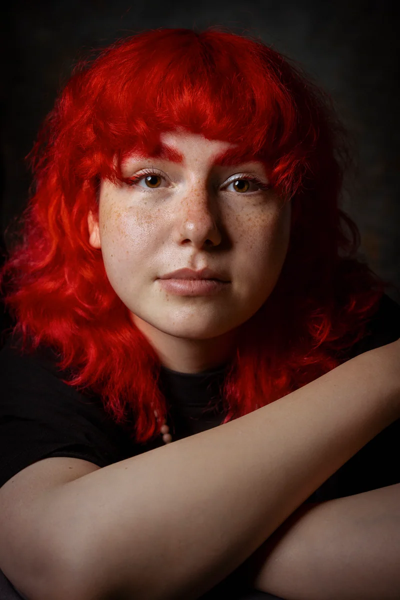 Freckled woman with bright red hair, her arms folded in front of her