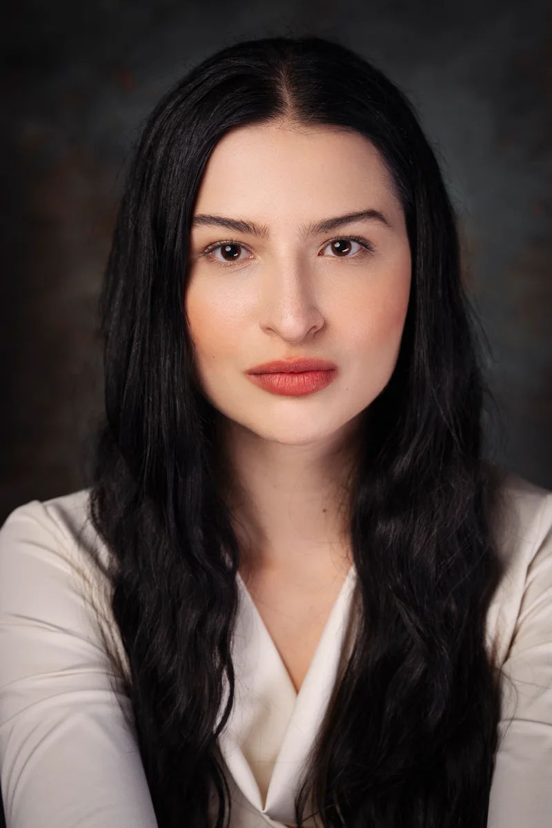 Woman with long black hair in a cream blouse facing the camera