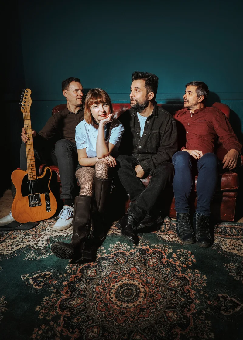 Band on a red sofa, the woman resting her chin on her hand