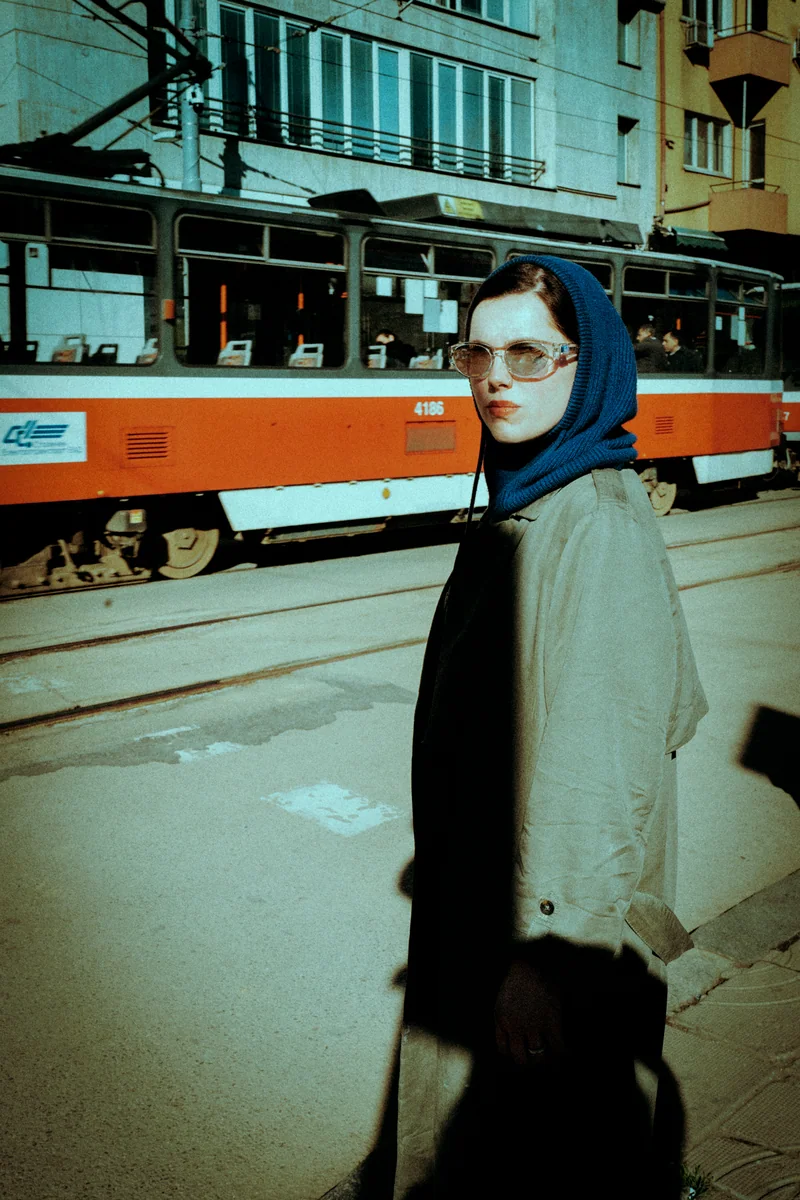 Woman in a blue headscarf and sunglasses in front of an orange tram