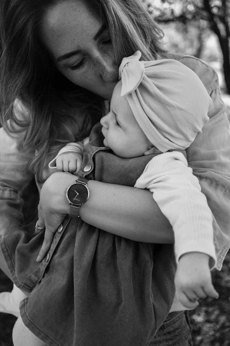 Woman kissing a baby in a bow headband, in black and white