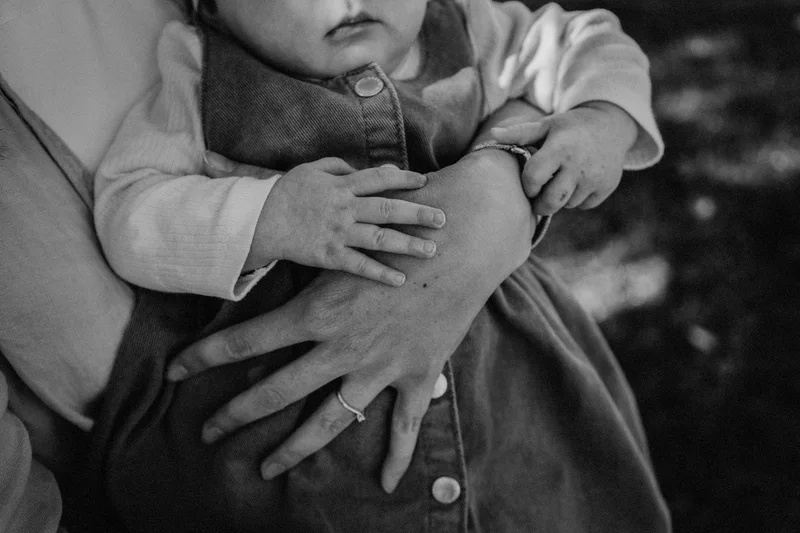 Adult hands holding a baby, a black and white detail