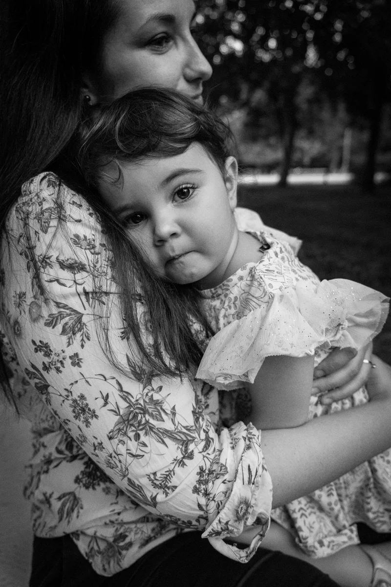 Woman holding a small child in a floral dress, in black and white