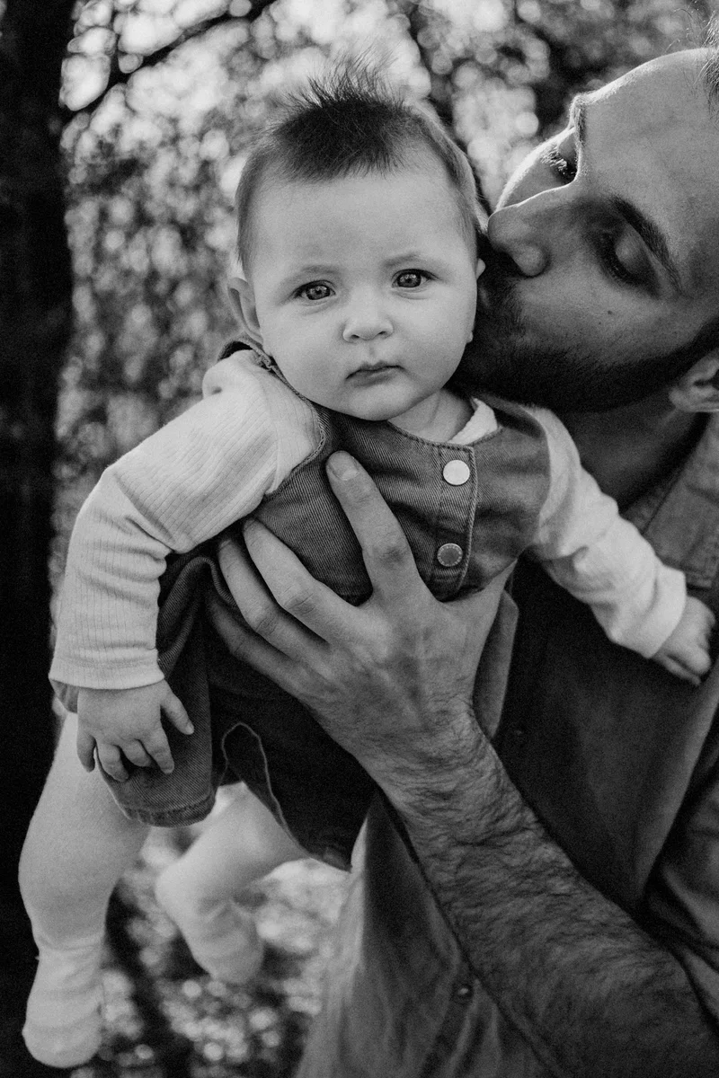 Man kissing a baby on the cheek, in black and white
