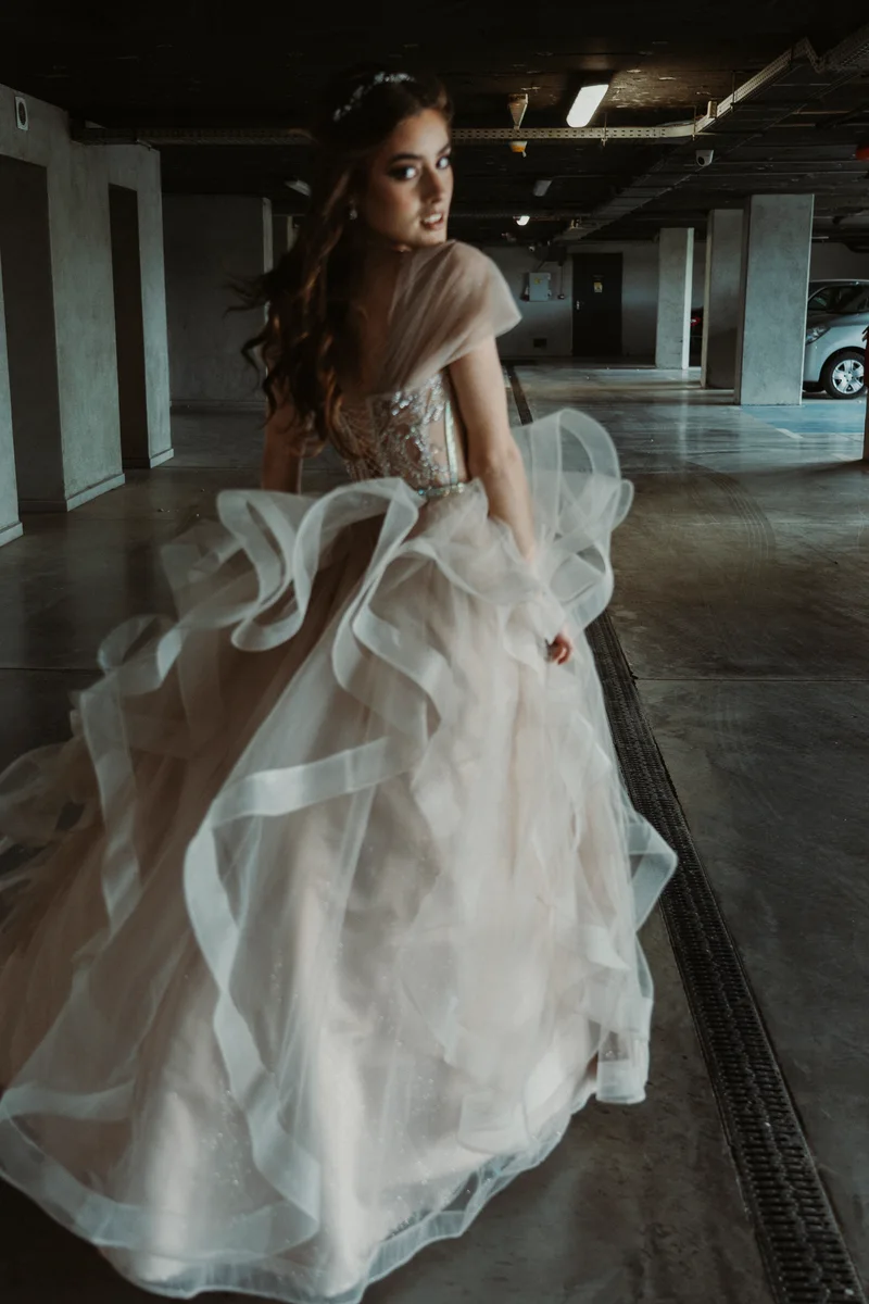 Woman in a pale dress with a long train turning in an underground garage