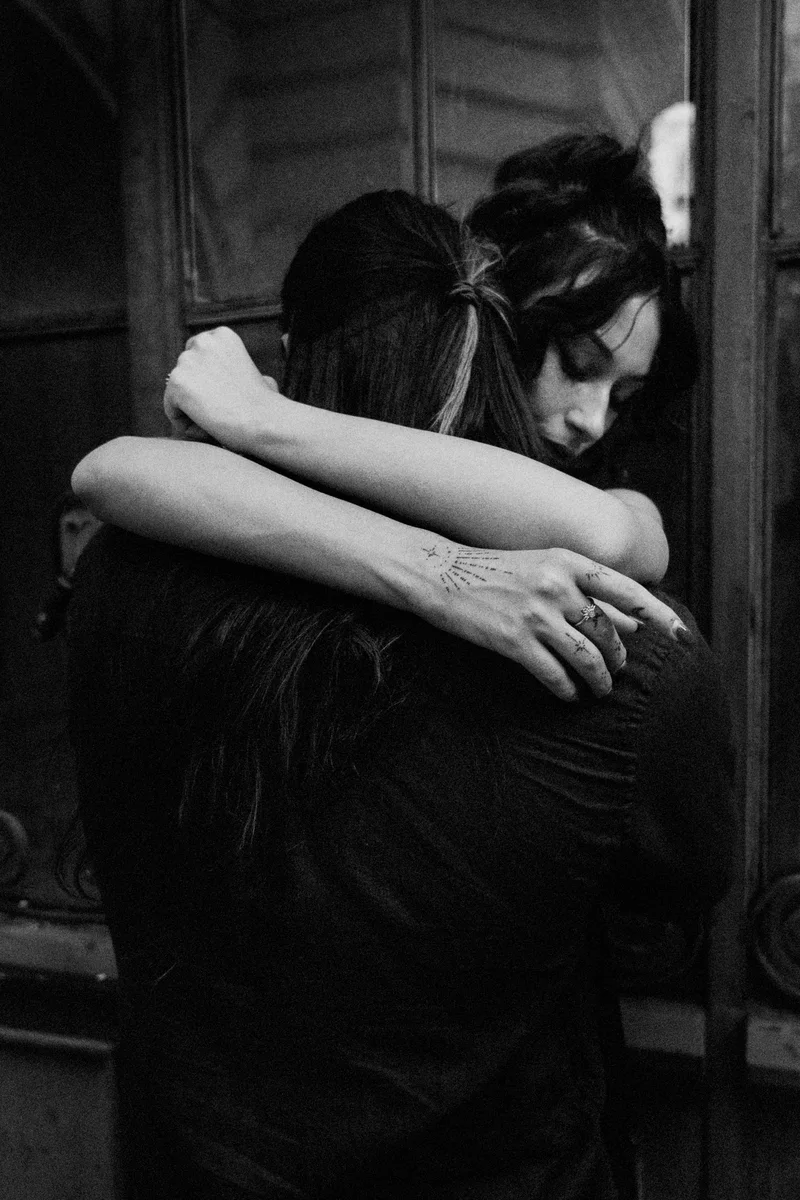 Woman with her arms around a man's neck by an old door, in black and white