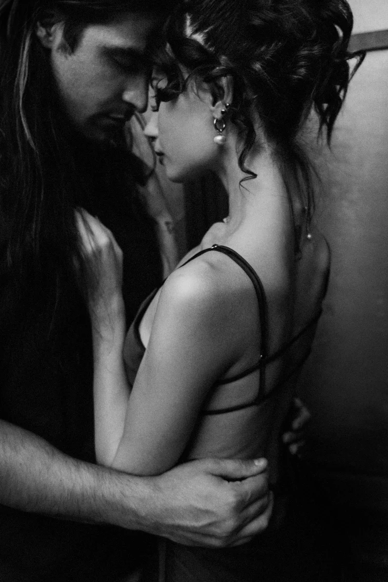 Couple face to face, his hand at her waist, in black and white