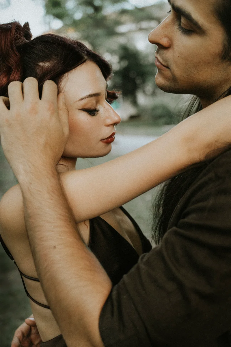 Man touching the hair of a woman who has her arm around his neck, outdoors