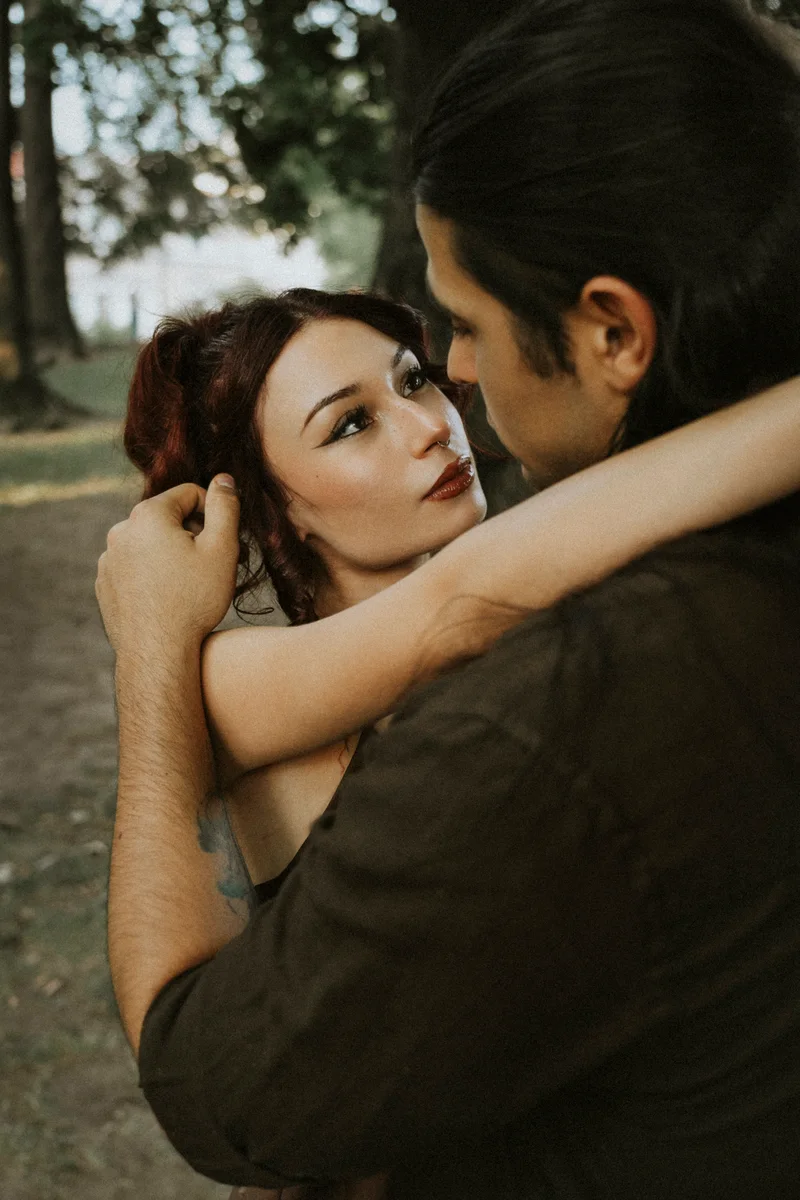 Woman gazing up at a man as they embrace under the trees