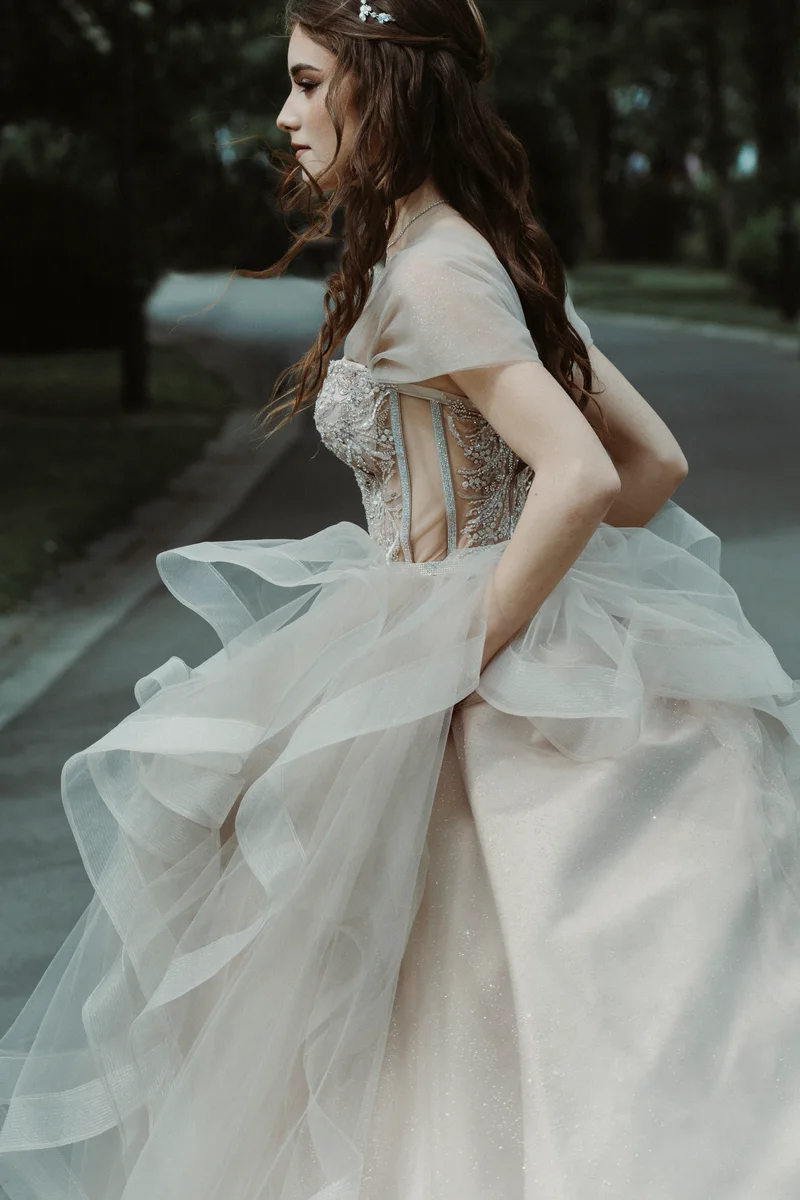 Woman in a long pale dress walking beside an outdoor concrete wall
