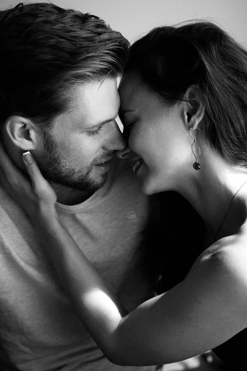 Close monochrome portrait of a couple touching foreheads with hands beside their faces