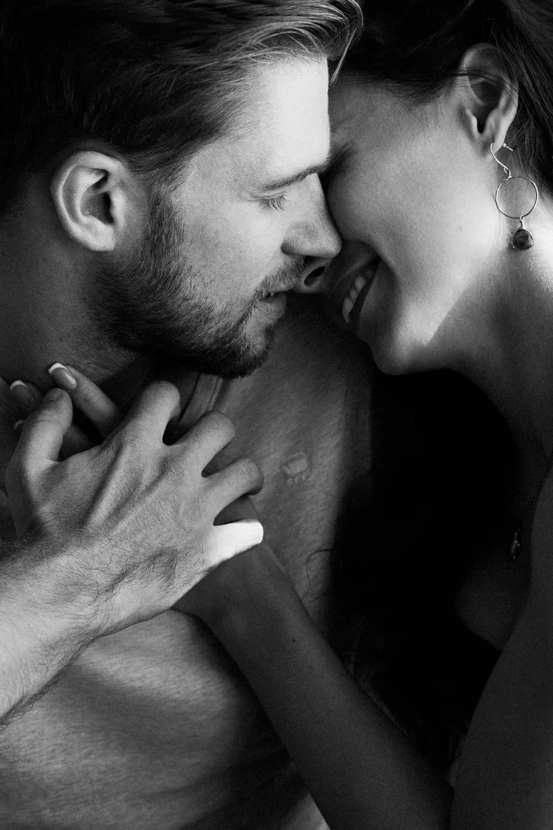 Man and woman with closed eyes and touching faces in a black and white photograph