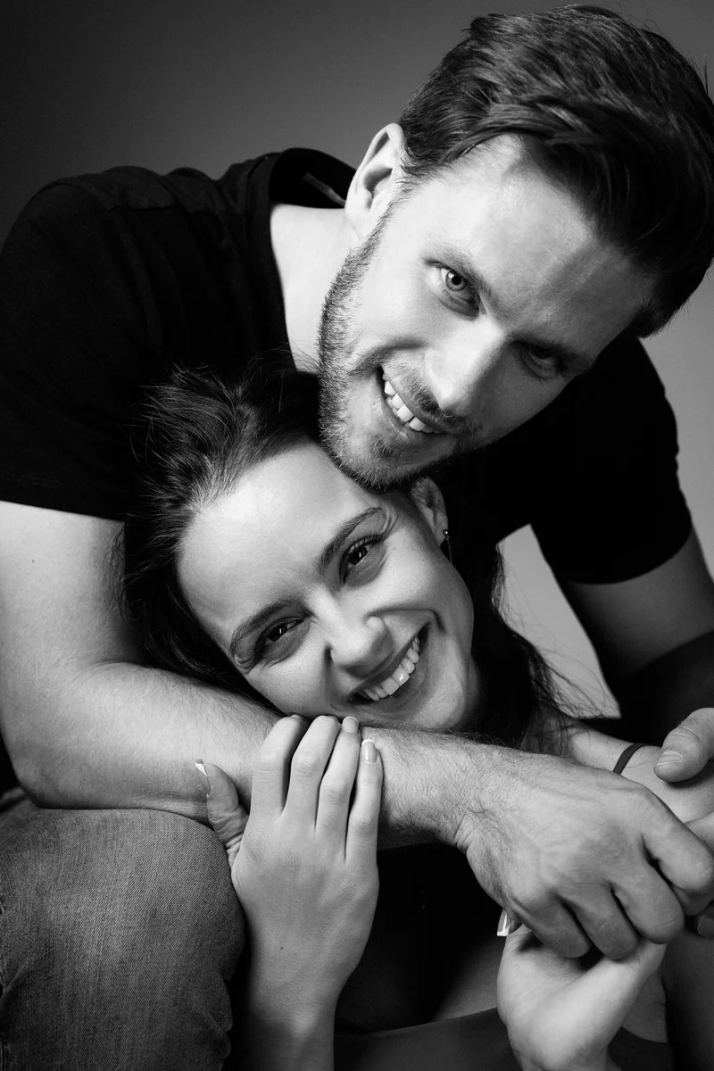 Smiling couple embracing with the man behind the woman in black and white