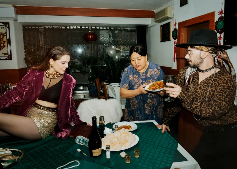 People in vintage clothing gathered around a table of food in a restaurant