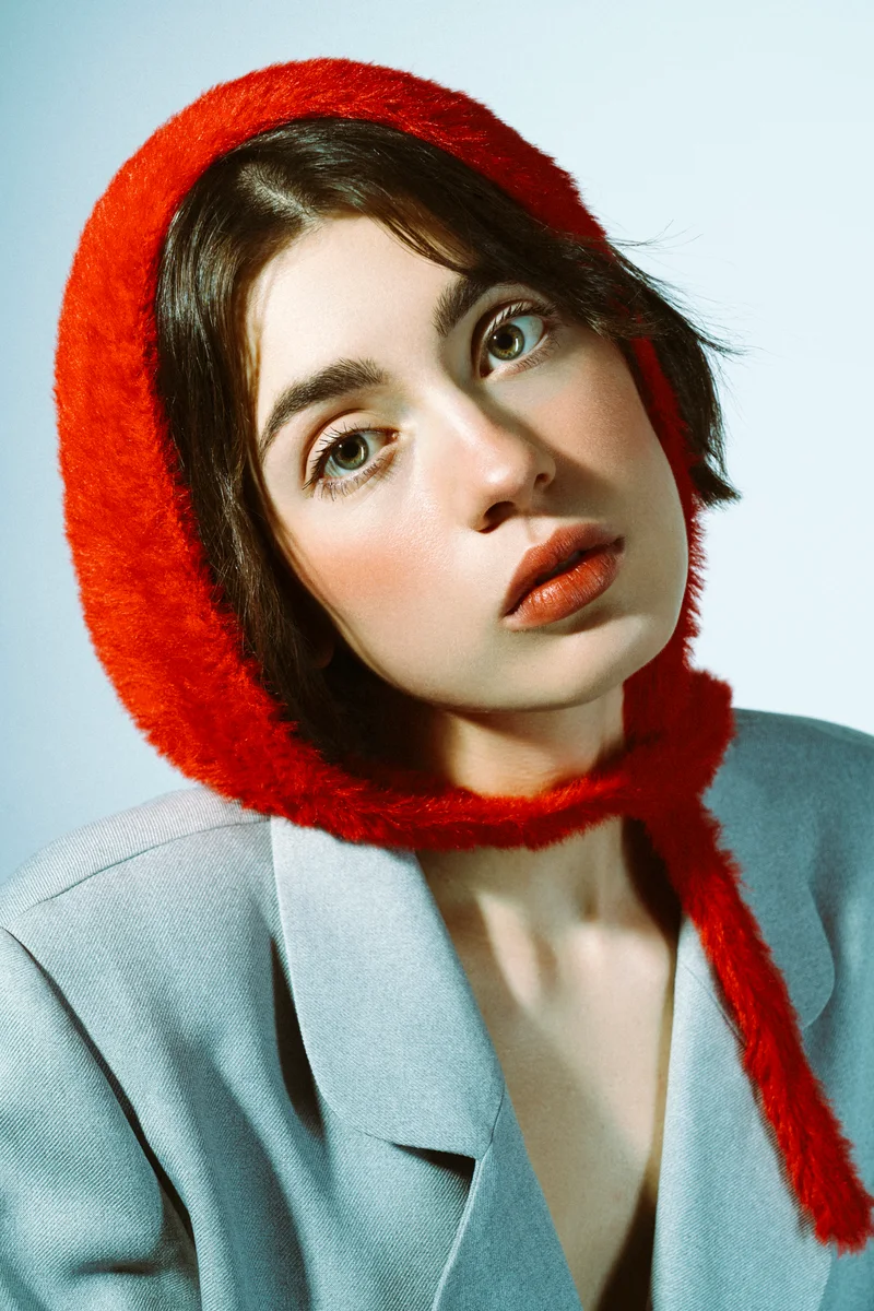 Close portrait of a woman in a red knitted bonnet and grey blazer