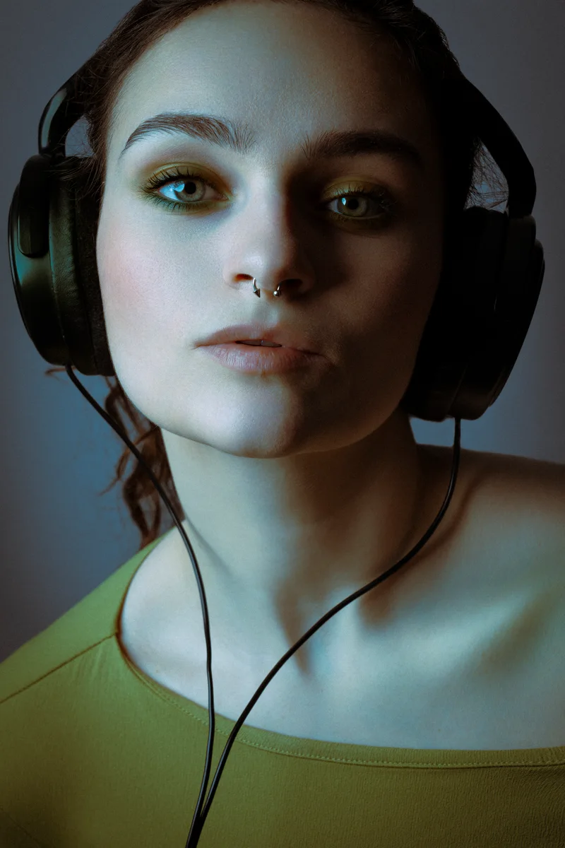Woman in headphones and a green top looking straight ahead in dim light