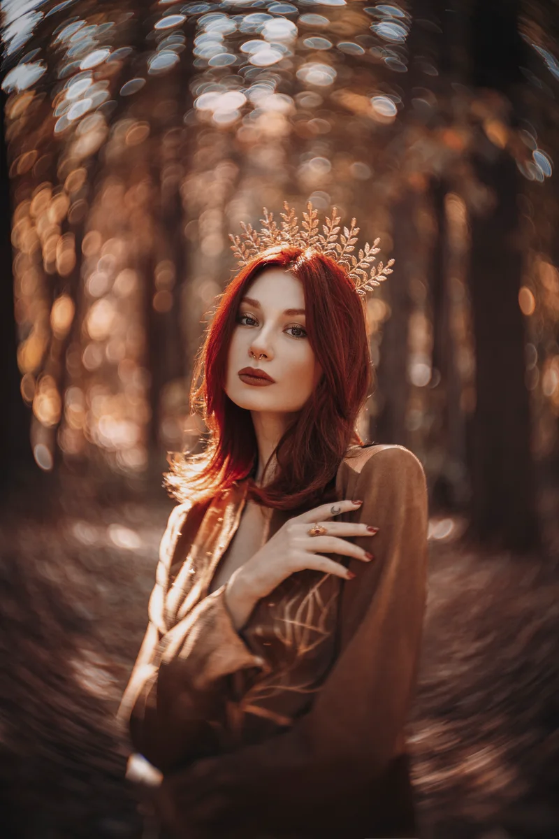 Red-haired woman wearing a golden crown in an autumn forest