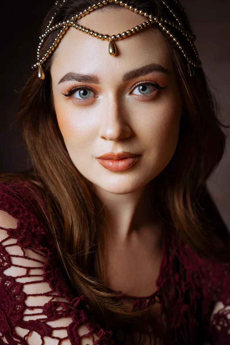 Woman wearing a beaded gold headpiece and a burgundy crochet top