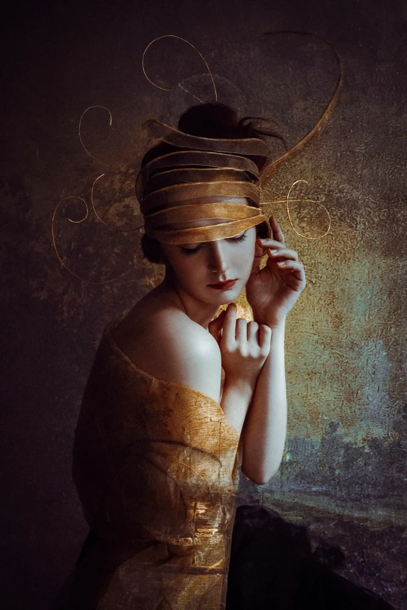 Woman with golden bands wrapped around her head and gold drapery against a textured backdrop