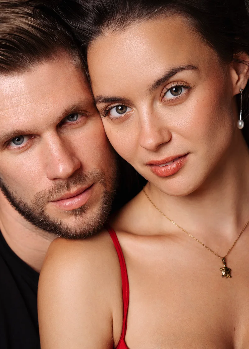 Close portrait of a couple with their faces touching and a red strap in the foreground