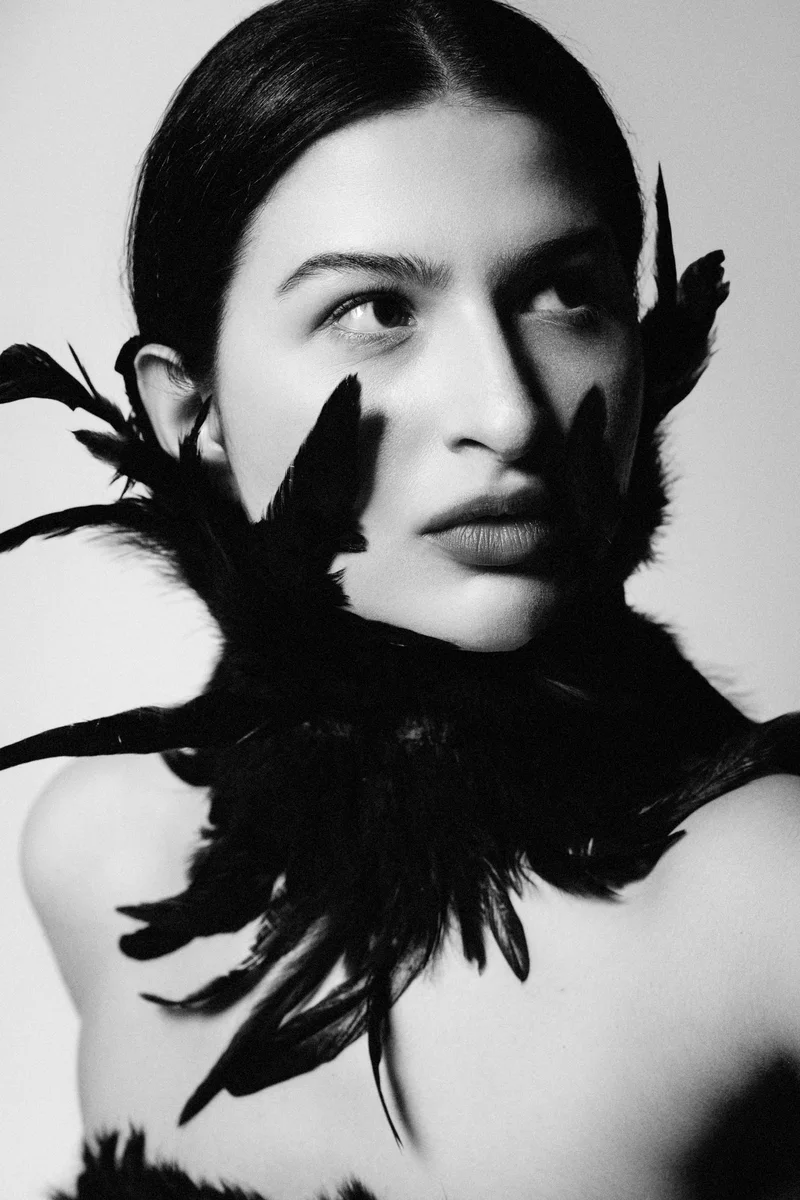 Black and white portrait of a woman with a collar of black feathers