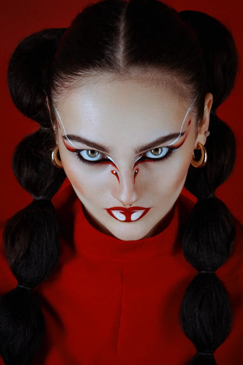Woman with graphic red and white make-up and bubble braids against red