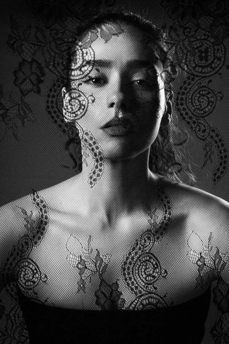 Black and white portrait of a woman with lace shadows across her face